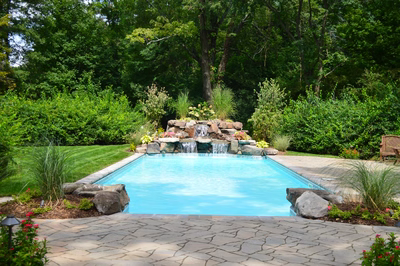 Morgan B - Saddle River, NJ - A backyard with a swimming pool surrounded by lush greenery and flowers