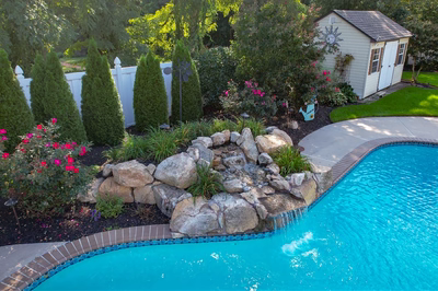 Multnomah E - West Deptford, NJ - A backyard with a swimming pool surrounded by lush greenery and flowers