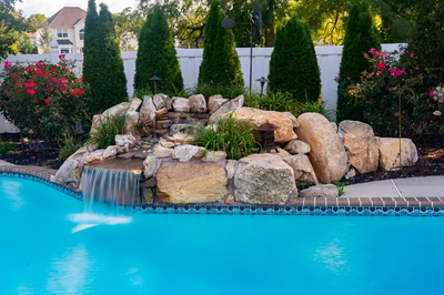 Multnomah I - West Deptford, NJ - A swimming pool with a waterfall in the middle surrounded by lush greenery and flowers