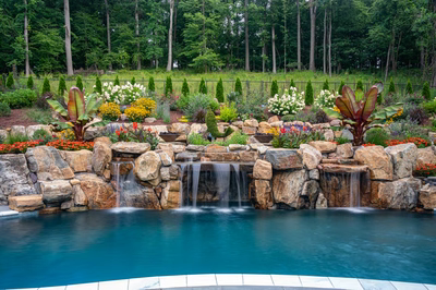 Munising A - Randolph, NJ - A swimming pool surrounded by lush greenery and colorful flowers with a waterfall feature