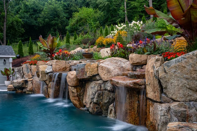 Munising J - Randolph, NJ - A lush garden with a waterfall and colorful flowers next to a swimming pool