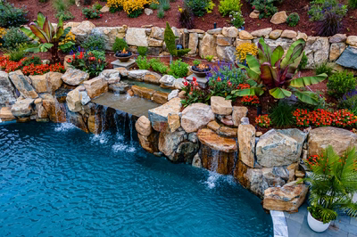 Munising O - Randolph, NJ - A swimming pool surrounded by a rock garden with a waterfall and colorful flowers