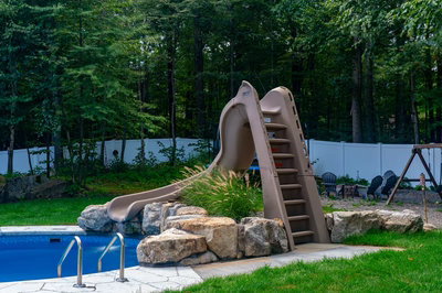 Myojin E - Sparta, NJ - A backyard with a pool and a slide surrounded by trees