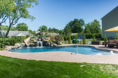 Myrtle A - Vineland, NJ - A backyard with a swimming pool and a water feature, surrounded by lush green grass