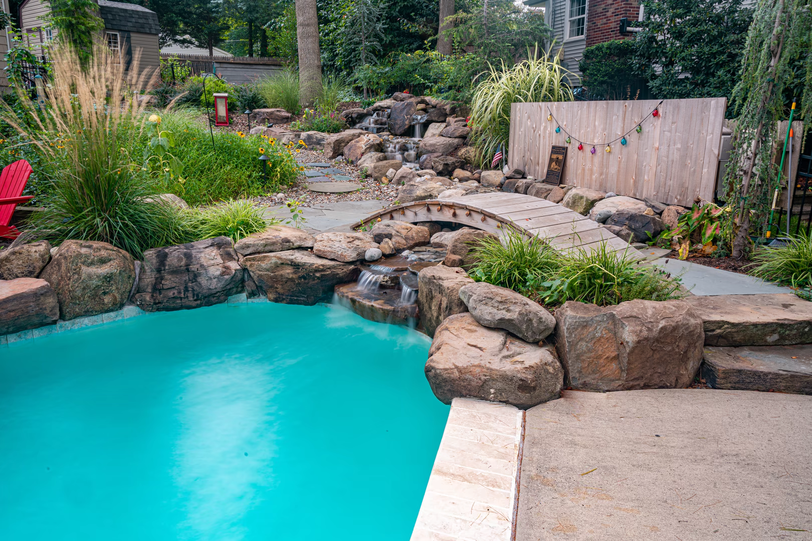 Natural stone boulder waterfall cascading into a pool amidst lush garden landscaping