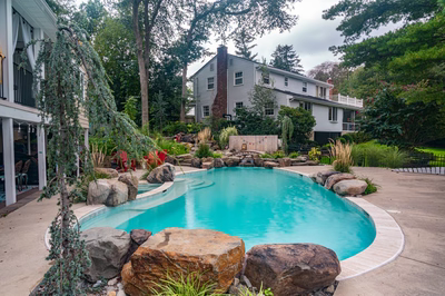Nachi H - Medford Lakes, NJ - A backyard with a swimming pool surrounded by rocks and greenery