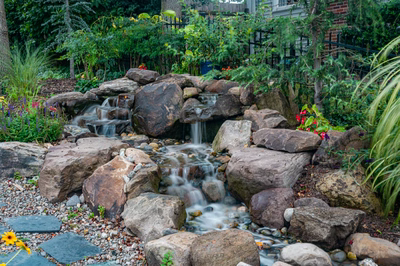 Nachi Q - Medford Lakes, NJ - A small waterfall surrounded by rocks and flowers in a garden.