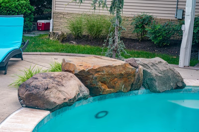 Nachi U - Medford Lakes, NJ - A swimming pool with rocks and a water feature in a backyard setting