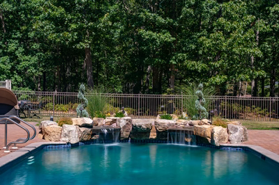 Naena G - Newfield, NJ - A swimming pool with a waterfall feature surrounded by lush greenery
