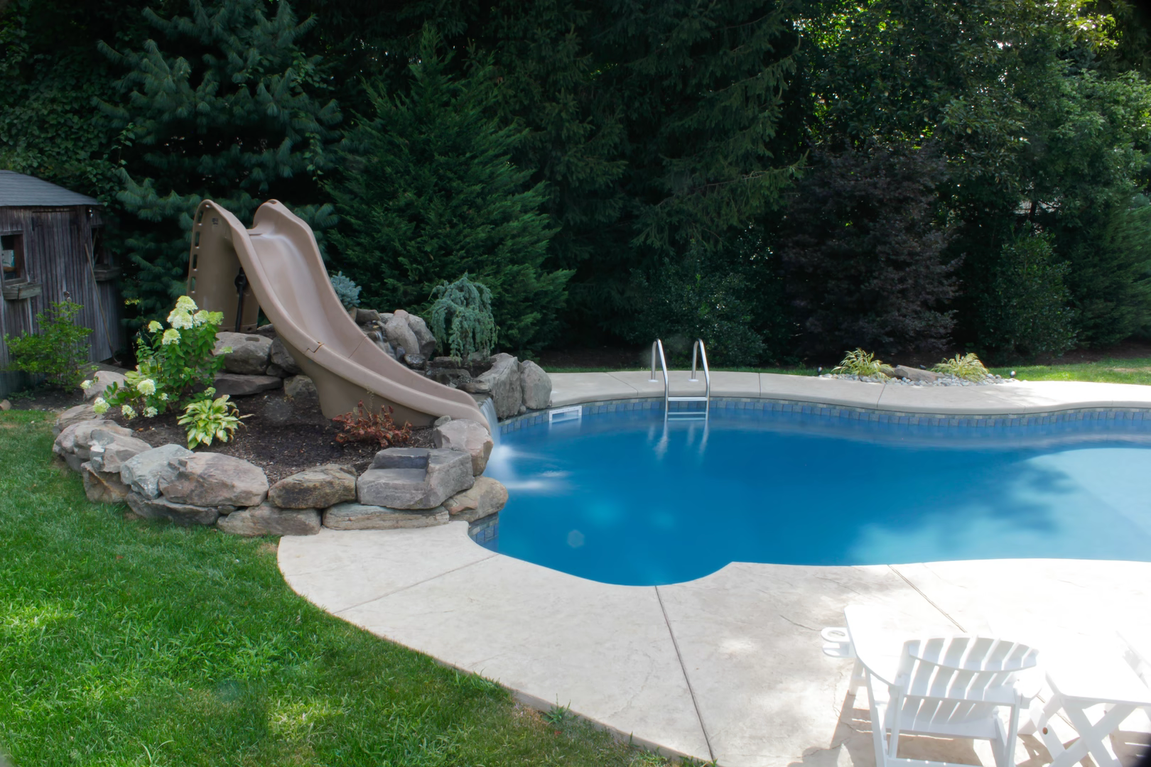 Natural stone boulder waterfall cascading into a freeform pool with lush garden landscaping