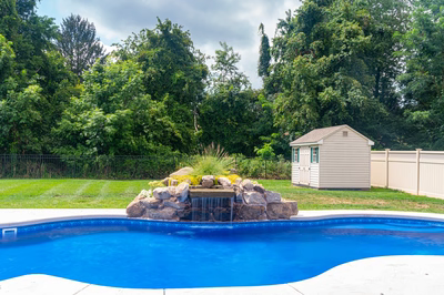 Okere B - Freehold, NJ - A backyard with a swimming pool and a small waterfall feature