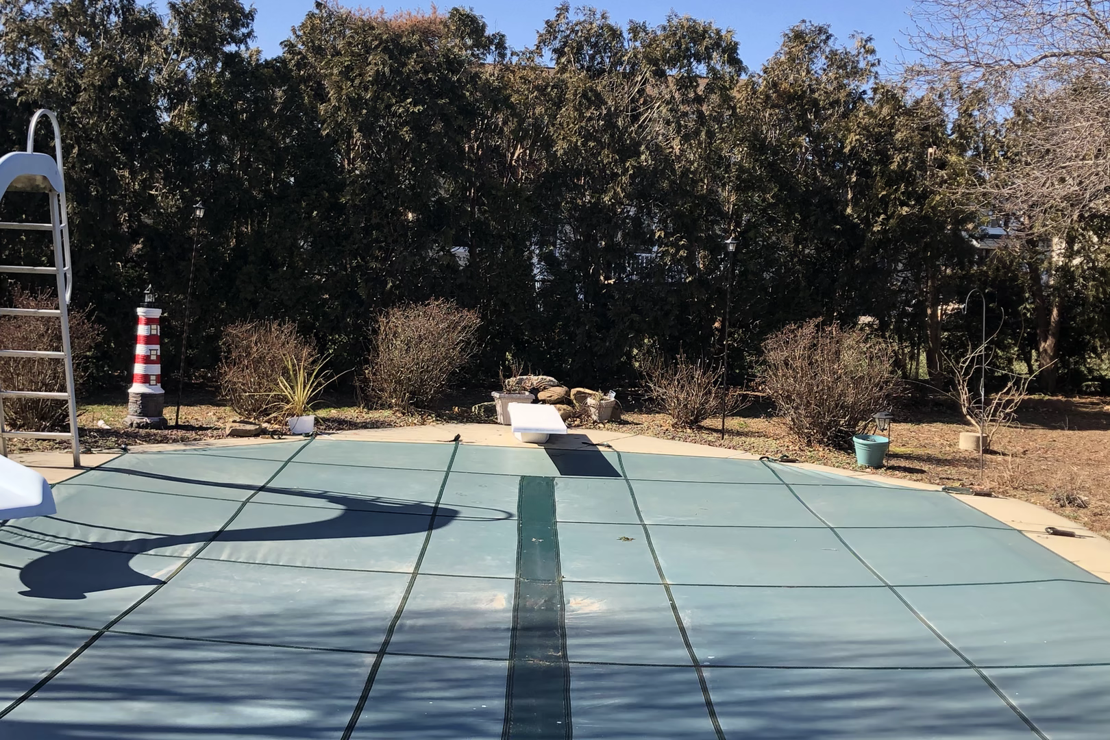Natural stone boulder waterfall cascading into a covered pool framed by dense shrubbery