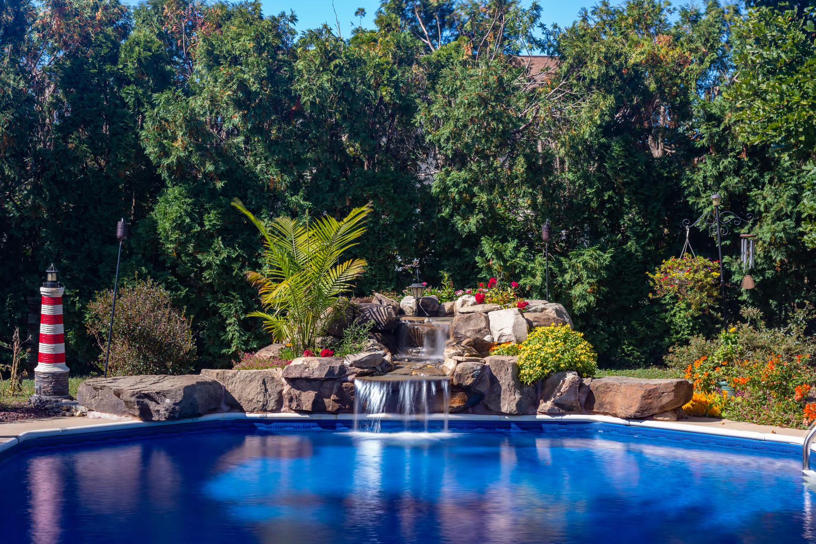 Natural stone boulder waterfall cascading into a pool surrounded by lush tropical plants