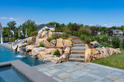 Otaki E - Ivyland, PA - A backyard with a swimming pool and a waterfall feature.