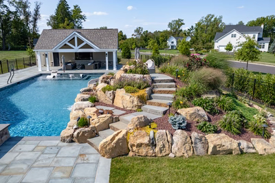 Otaki F - Ivyland, PA - A backyard with a swimming pool and landscaping featuring rocks and plants