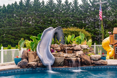 Otodome A - Tinton Falls, NJ - A backyard pool with a water feature and a playhouse in the background
