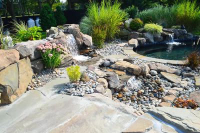 Paradise F - Moorestown, NJ - A backyard with a water feature and a slide, surrounded by lush greenery