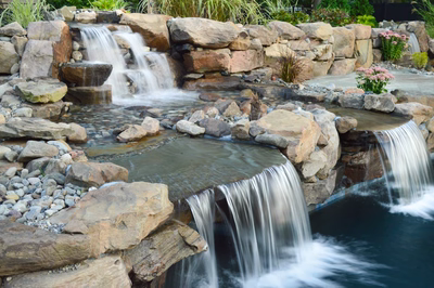 Paradise I - Moorestown, NJ - A backyard with a pool and a waterfall surrounded by lush greenery
