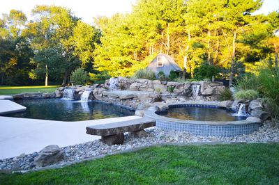 Paradise N - Moorestown, NJ - A backyard with a pond, waterfall, and bench surrounded by trees