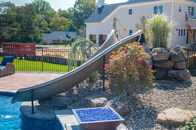 Pearl E - Lincroft, NJ - A backyard with a water feature and a slide.