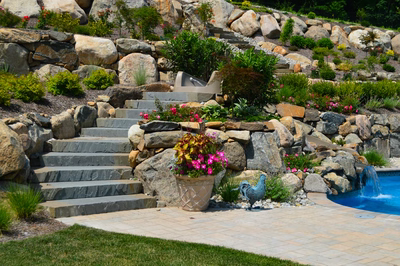 Pinnacle C - Towaco, NJ - A landscaped backyard with a stone retaining wall and steps leading to a swimming pool