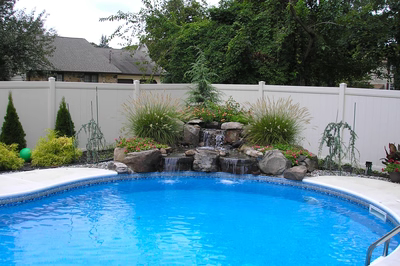 Pirere-A - A pool with a water feature and a slide in a backyard setting