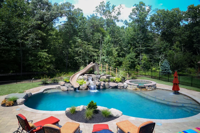 Pongour A - Mt. Laurel, NJ - A swimming pool with a waterfall and a slide surrounded by lush greenery