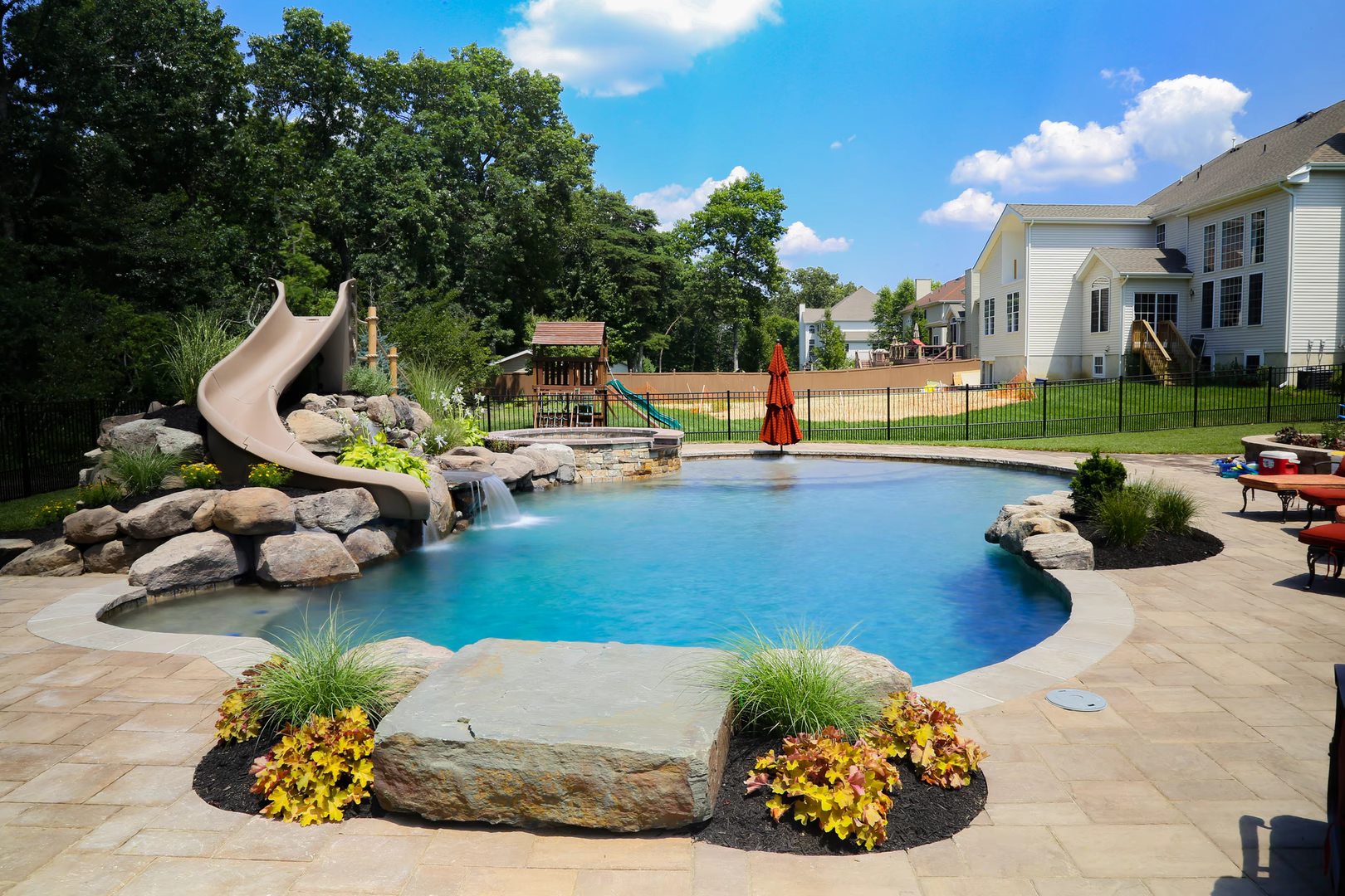Cascading natural stone boulder waterfall spilling into a freeform pool with lush garden landscaping