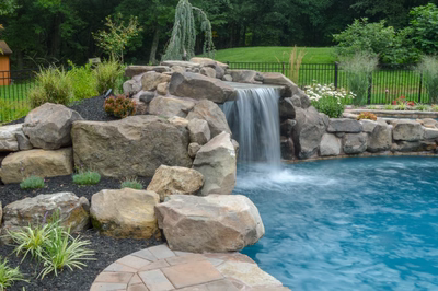 Prenn D - Limerick, PA - A large rock waterfall in the middle of a swimming pool surrounded by lush greenery