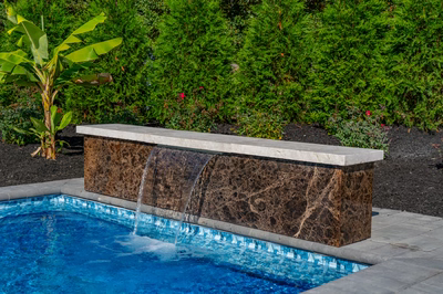 Formal B - Forrest Hills, MD - A rectangular pool with a waterfall feature in the middle of a lush green garden