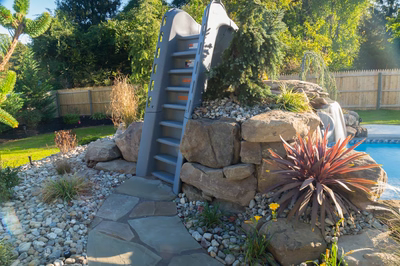 Rainbow C - Middletown, NJ - A backyard with a rock waterfall and a climbing wall next to a swimming pool