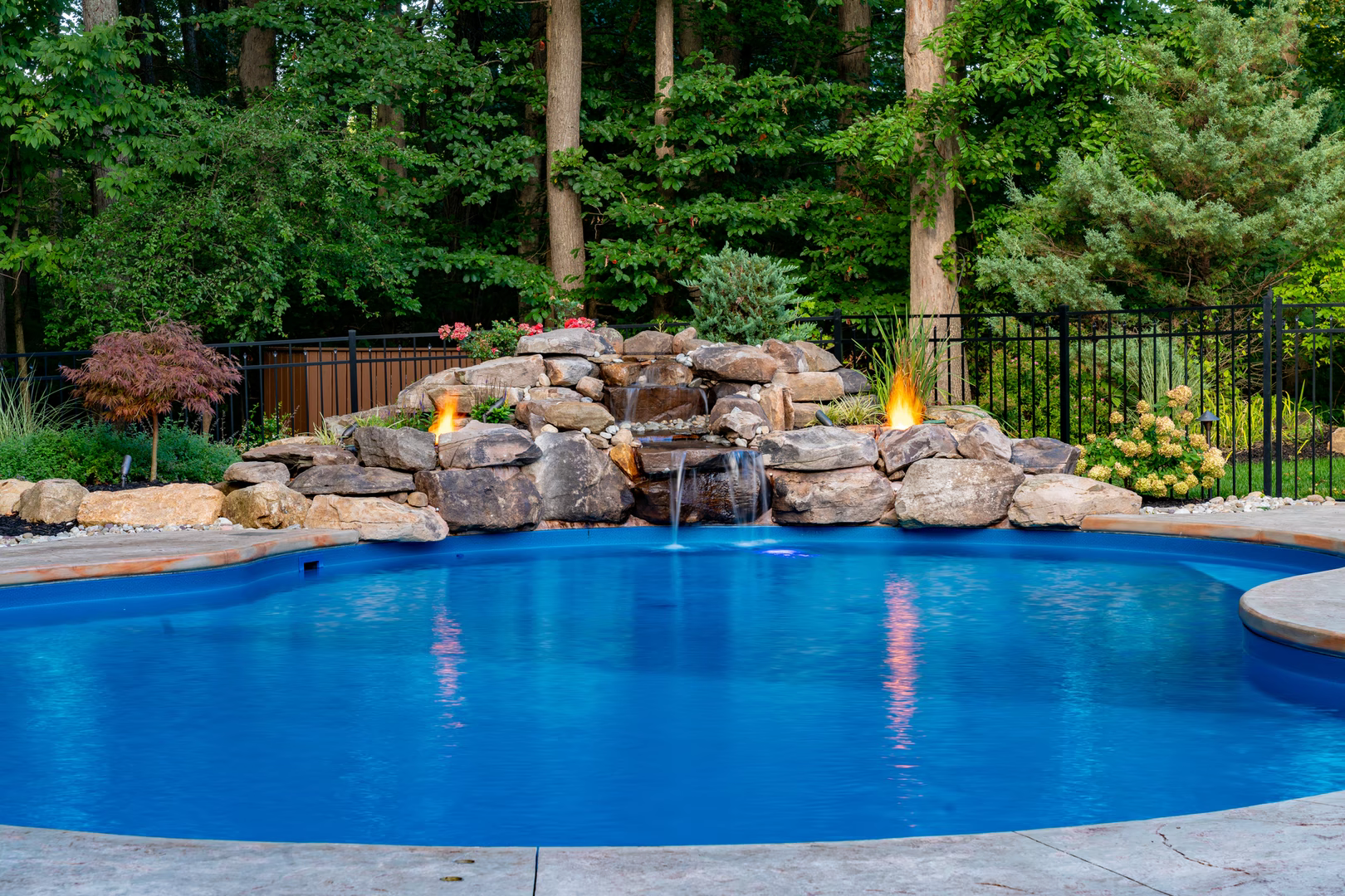Natural stone boulder waterfall cascading into a blue pool surrounded by lush greenery