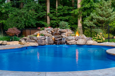 Ramona A - Bloomsbury, NJ - A swimming pool with a waterfall and fire pit surrounded by lush greenery