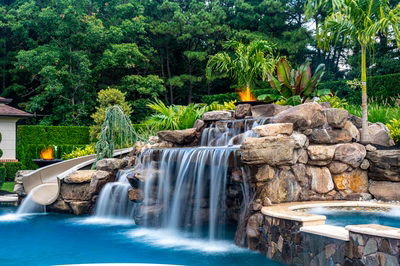 Richetli C - Monroe, NJ - A pool with a waterfall and a water feature surrounded by lush greenery