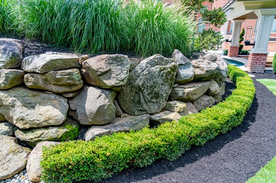 Richetli J - Monroe, NJ - A stone retaining wall in front of a brick house.