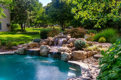 Ripon F - Red Bank, NJ - A backyard with a swimming pool and a waterfall surrounded by lush greenery