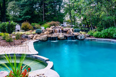 Ripon L - Red Bank, NJ - A swimming pool surrounded by lush greenery and a waterfall.