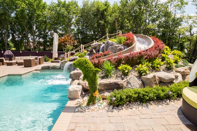 Roesch C - Englishtown, NJ - A backyard with a water feature and a water slide surrounded by lush greenery