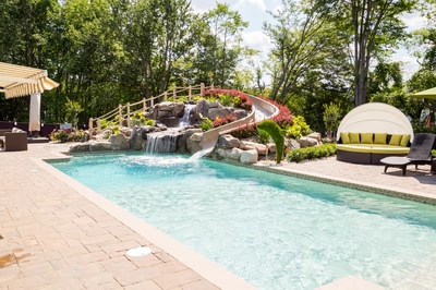 Roesch E - Englishtown, NJ - A swimming pool with a waterfall and a water feature surrounded by lush greenery