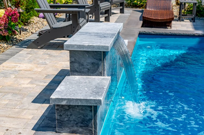 Rome C - Long Beach Island, NJ - A swimming pool with a waterfall feature in the middle of it surrounded by colorful flowers and patio furniture