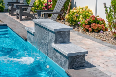 Rome D - Long Beach Island, NJ - A swimming pool with a waterfall feature surrounded by colorful flowers and plants