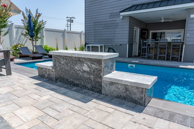 Rome F - Long Beach Island, NJ - A backyard with a pool and patio area featuring a stone bar and lounge chairs
