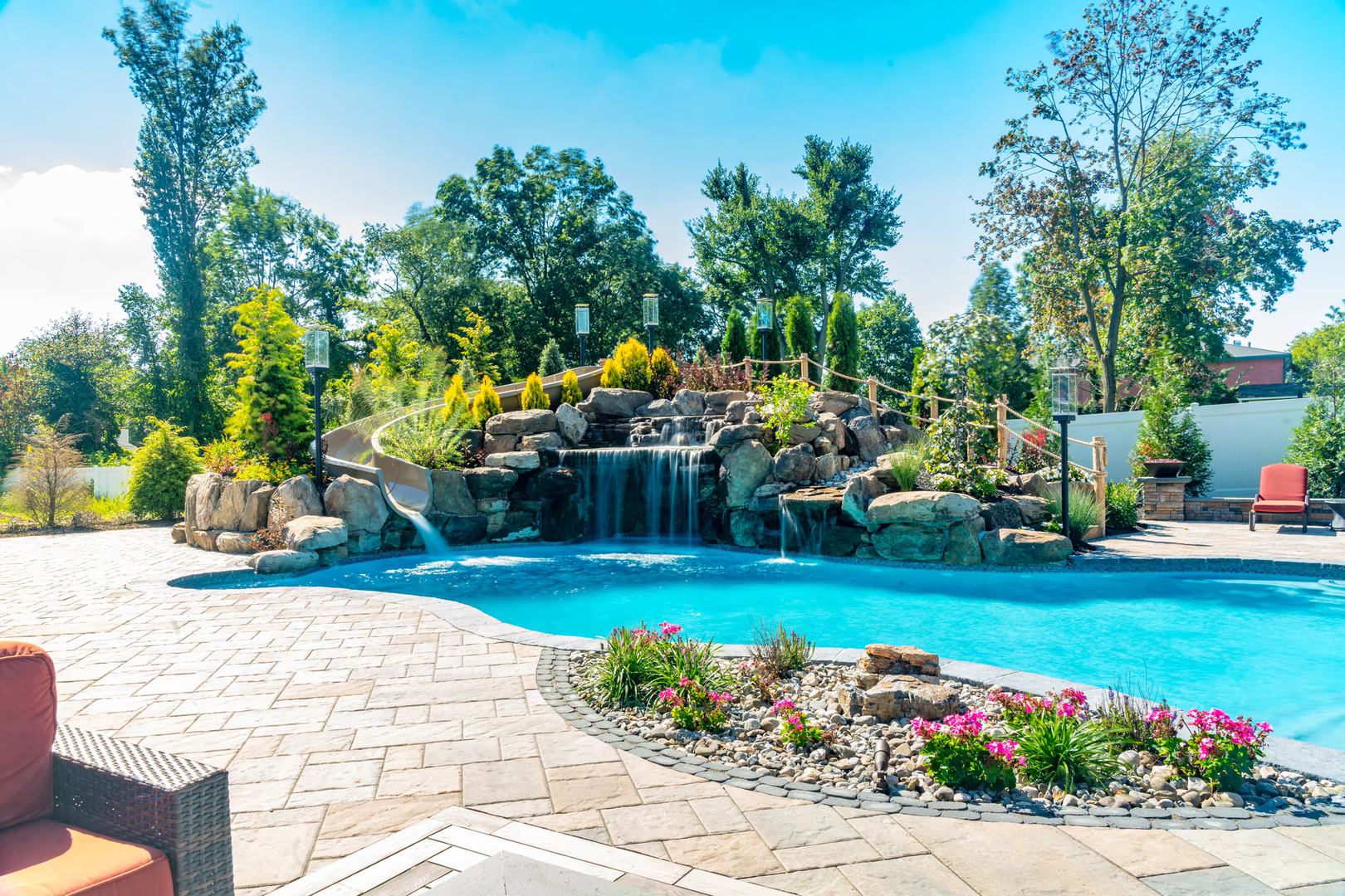 Natural stone boulder waterfall cascades into a freeform pool with lush garden landscaping