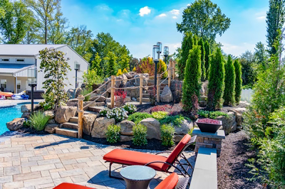Russell H - Maple Shade, NJ - A backyard with a pool and landscaping featuring rocks, plants, and trees
