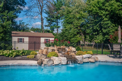 Ryuzu E - Collegeville, PA - A swimming pool with a waterfall in the middle surrounded by lush greenery and flowers