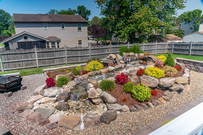 Sendo B - Sewell, NJ - A backyard garden with a small waterfall surrounded by colorful flowers and rocks