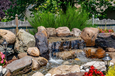 Sendo D - Sewell, NJ - A small waterfall surrounded by rocks and flowers in a garden setting