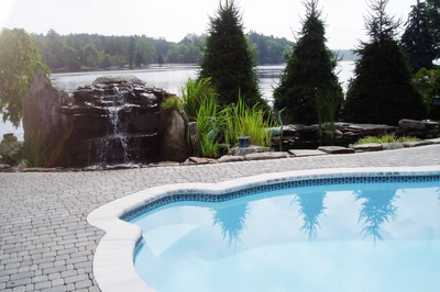 Shebelle - Hammonton, NJ - A swimming pool with a waterfall and a pond in the background
