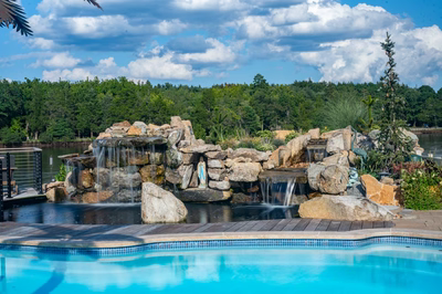 Shebelle - Hammonton, NJ - A large rock waterfall in the middle of a swimming pool surrounded by lush greenery