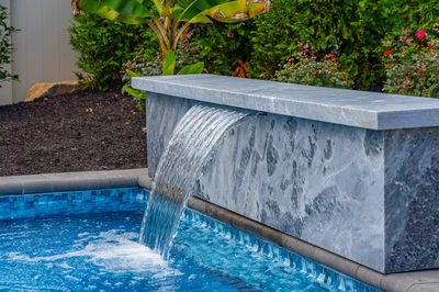 Formal G -  - A water feature in a swimming pool surrounded by greenery and flowers